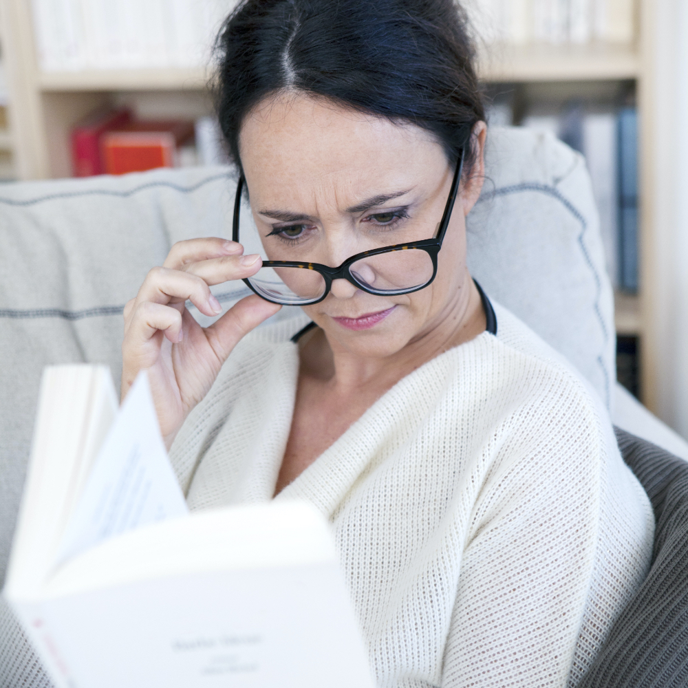 Femme portant des lunettes qui essaie de lire un livre