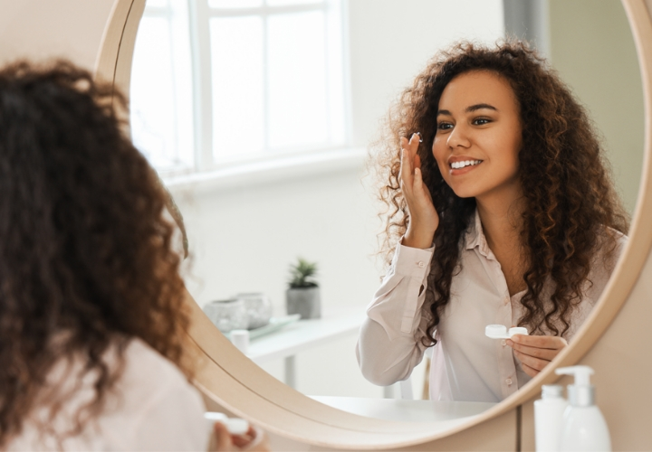 Woman looking in mirror inserting lenses