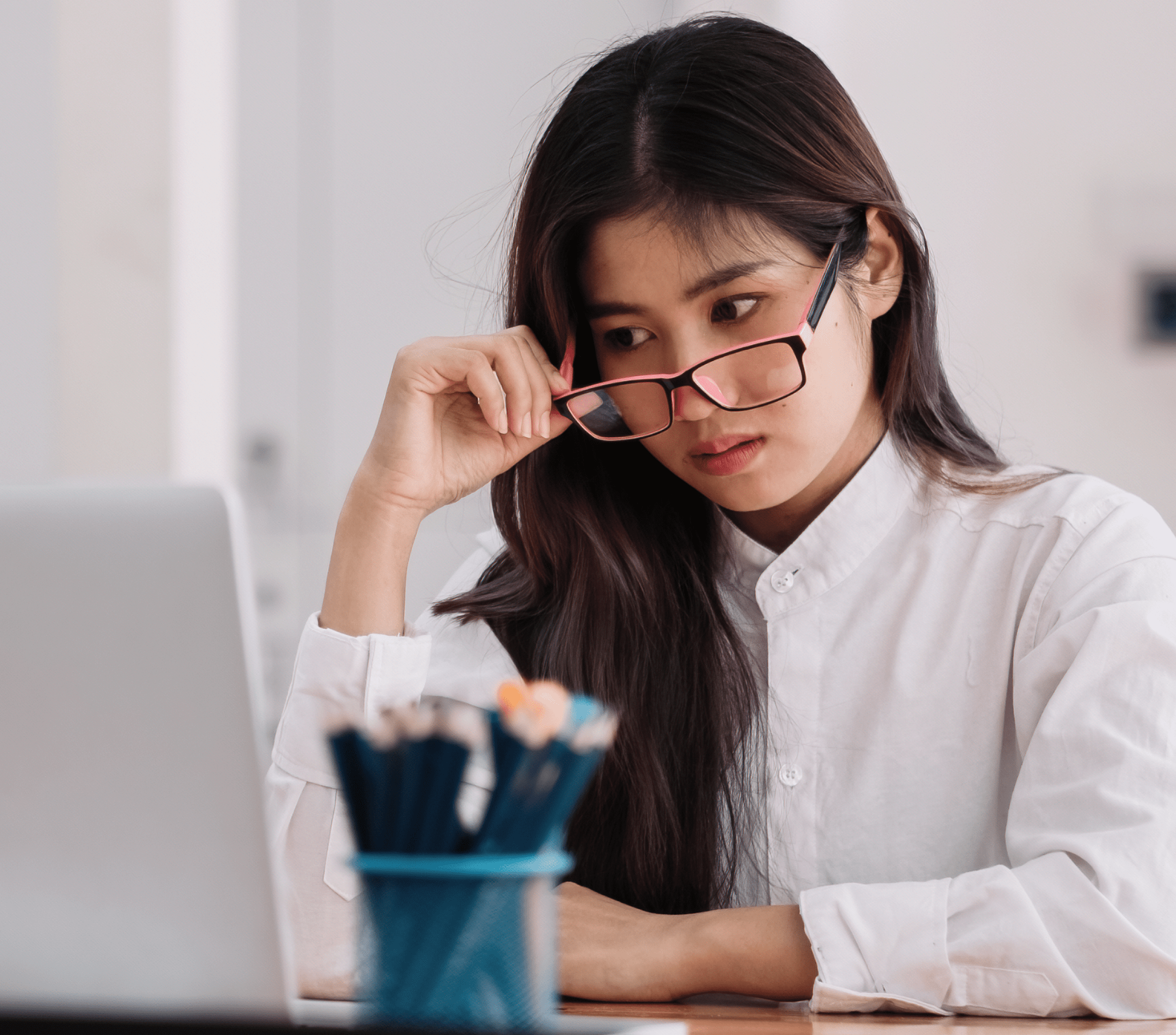 Woman removing glasses to look at laptop