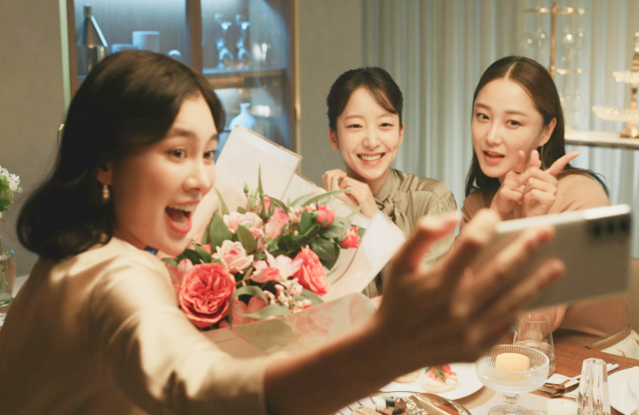 Woman using a phone to take a selfie photo with two other women